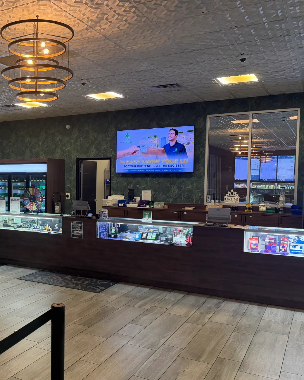 The service counter, with a wall screen asking customers to show ID to their budtender at the register.