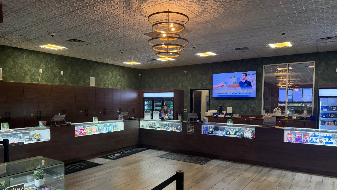 The service counter, with a wall screen asking customers to show ID to their budtender at the register.
