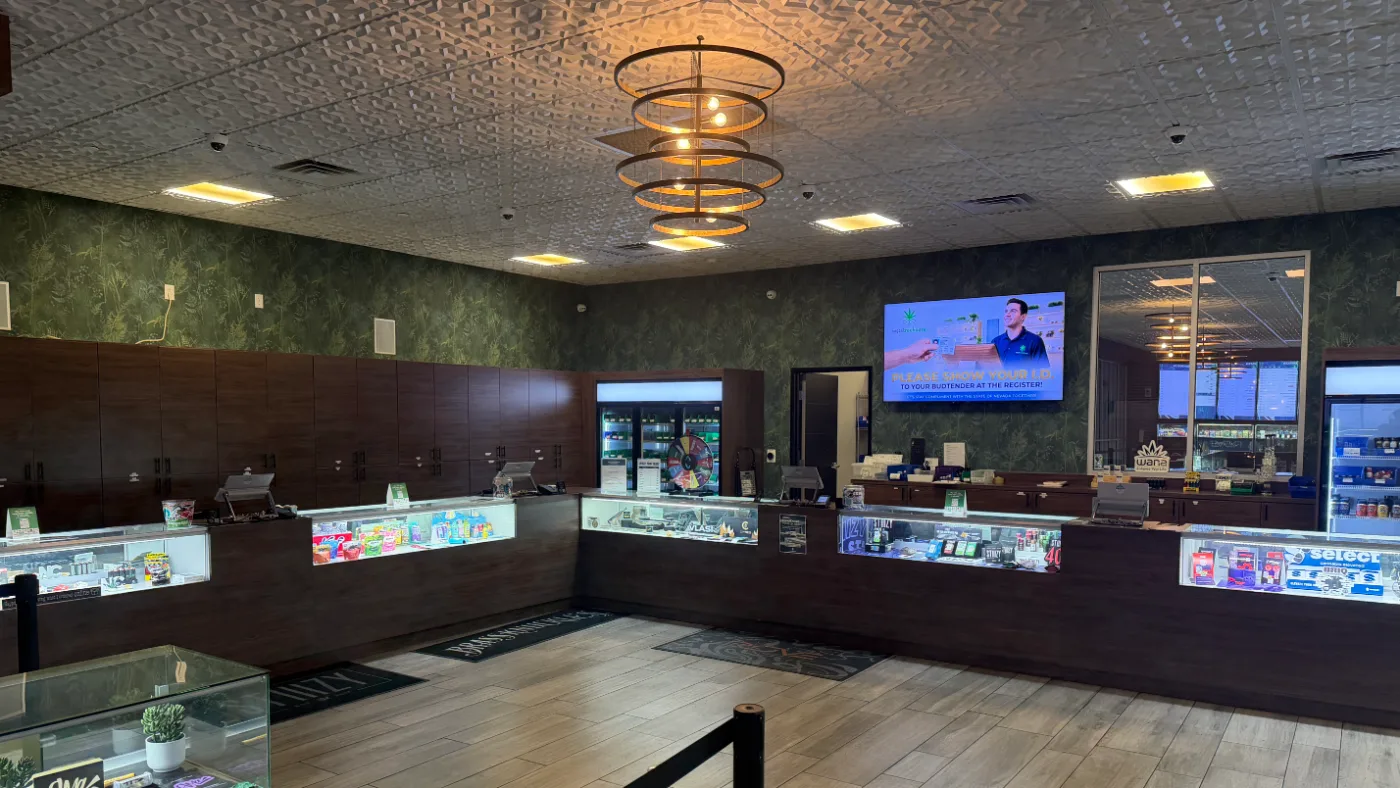 The sales floor at 4660 S Decatur: a counter running two walls, lit display cases beneath a dark wood cabinet run.